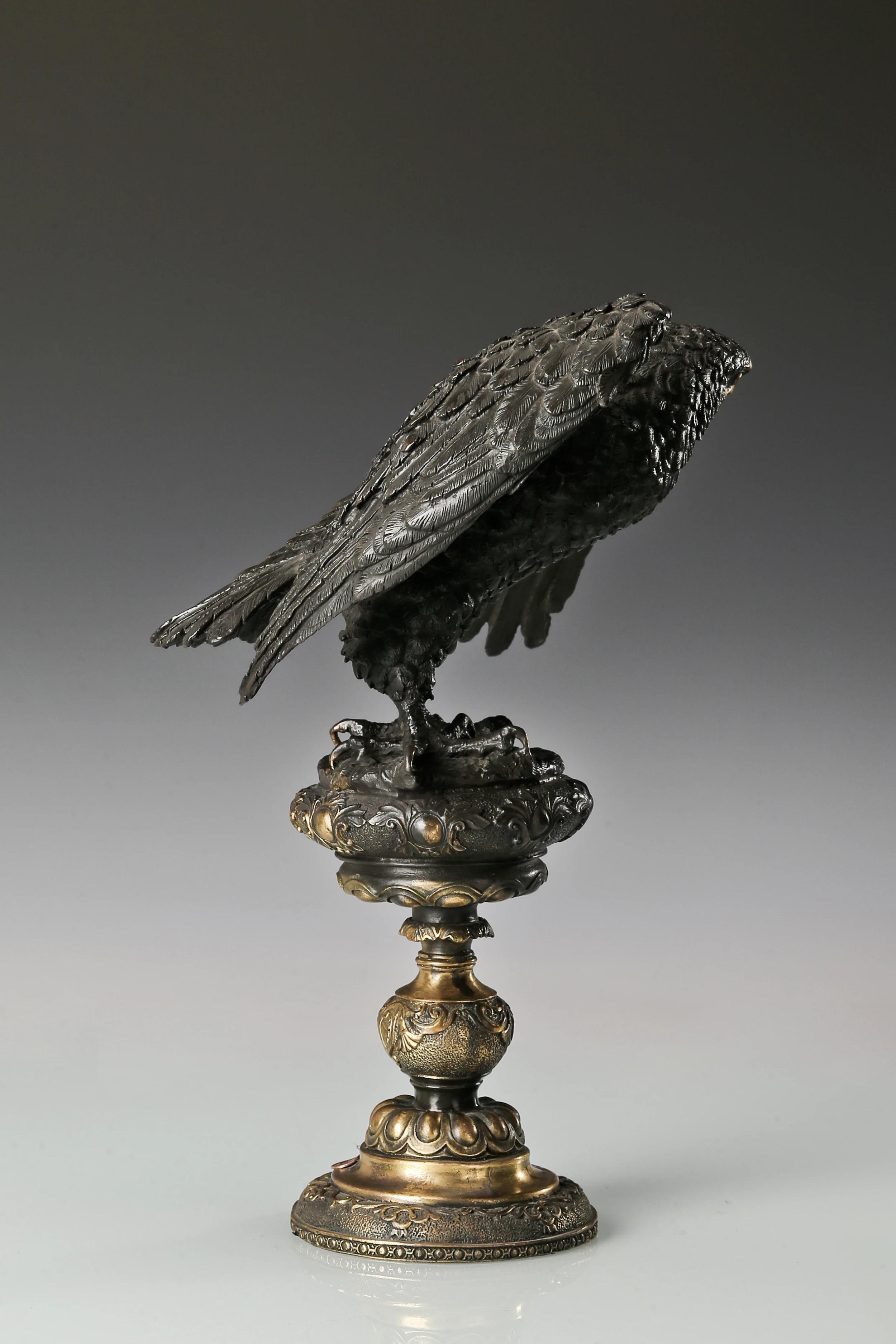 Elegant bronze eagle sculpture with ornate pedestal and detailed feathers. A refined statement piece symbolizing strength, control, and authority.