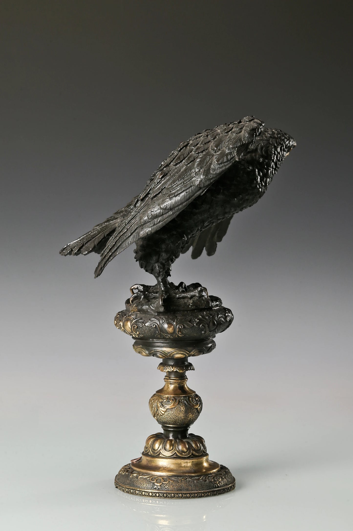 Elegant bronze eagle sculpture with ornate pedestal and detailed feathers. A refined statement piece symbolizing strength, control, and authority.