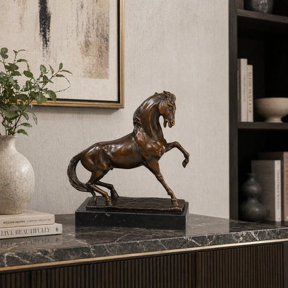 Refined prancing bronze horse sculpture with raised foreleg and flowing mane, realistic equestrian statue on black marble base, lost wax casting fine art.