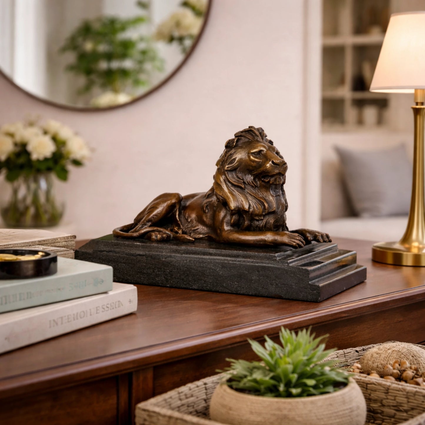 This is a majestic bronze lion sculpture, cast using the lost-wax method, depicting the animal in a poised, reclining stance. The sculpture features a rich, warm bronze patina with a smooth, polished finish that accentuates the lion’s powerful musculature and the intricate, flowing details of its mane. Its head is held high, conveying a sense of quiet authority and regal composure, while its body rests in a relaxed yet alert posture.
