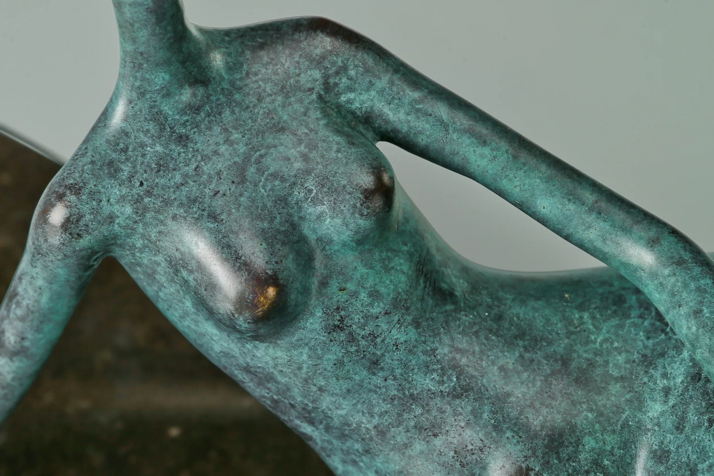 Close-up of sculpted female torso and handcrafted green bronze patina