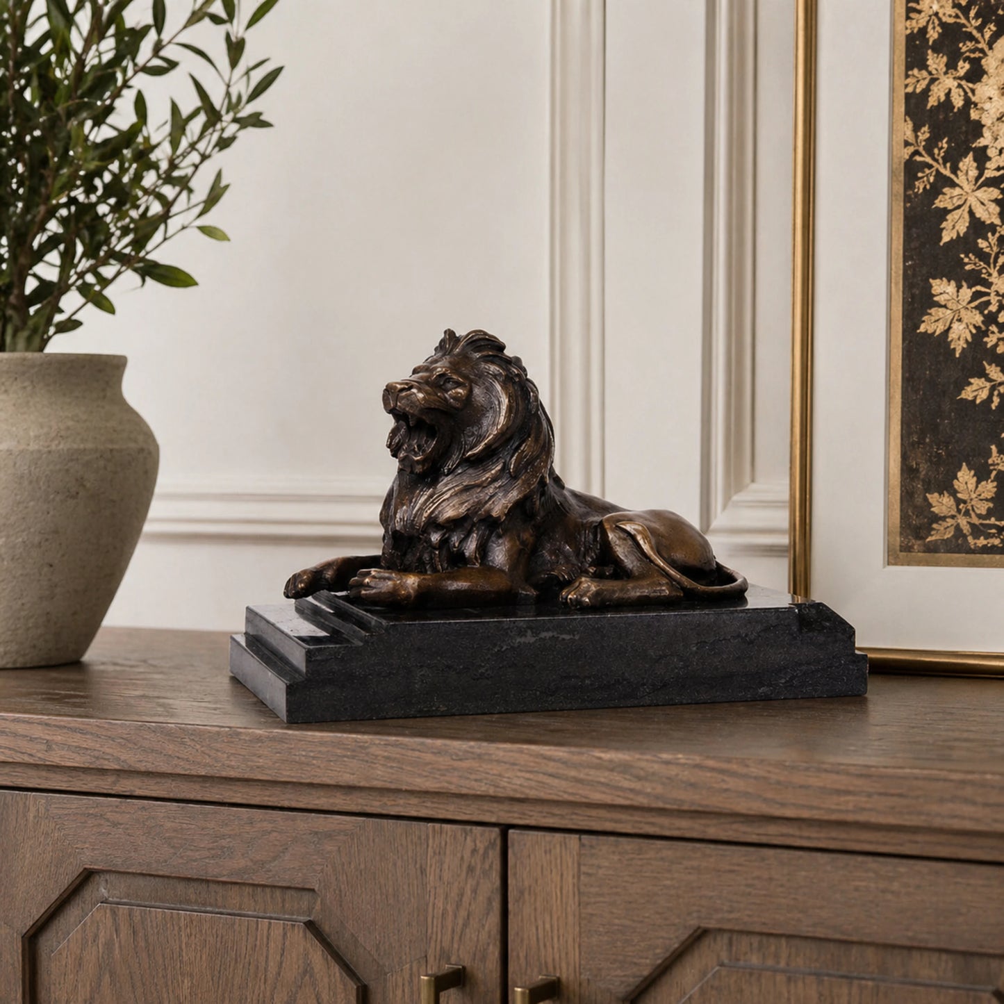 This is a powerful bronze lion sculpture, cast using the lost-wax method, depicting the animal in a reclining pose with its mouth open in a fierce roar. The sculpture features a rich, aged bronze patina that highlights the intricate, flowing details of its mane and the taut musculature of its body, conveying a sense of primal strength and authority. The lion’s head is raised, and its expression is intense, while its body rests in a relaxed yet alert posture, suggesting a moment of warning or dominance.
