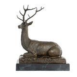 Left side view of seated bronze stag sculpture with realistic body details and branching antlers