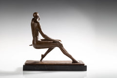 Side angled view of seated female bronze sculpture with long extended legs