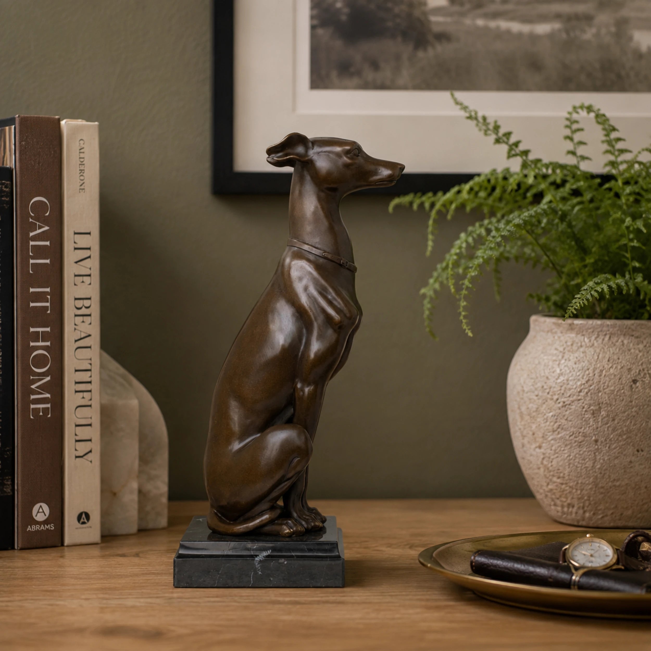 Seated Greyhound Bronze Sculpture displayed in a styled interior