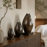 Set of three abstract cat bronze sculptures in graduated sizes displayed on a modern console