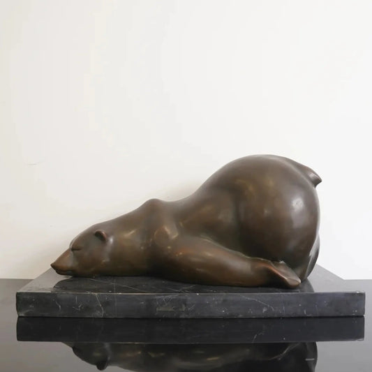 Sleeping polar bear bronze sculpture resting on a black marble base