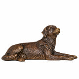 Handcrafted small bronze lying dog sculpture in a relaxed resting pose with head raised