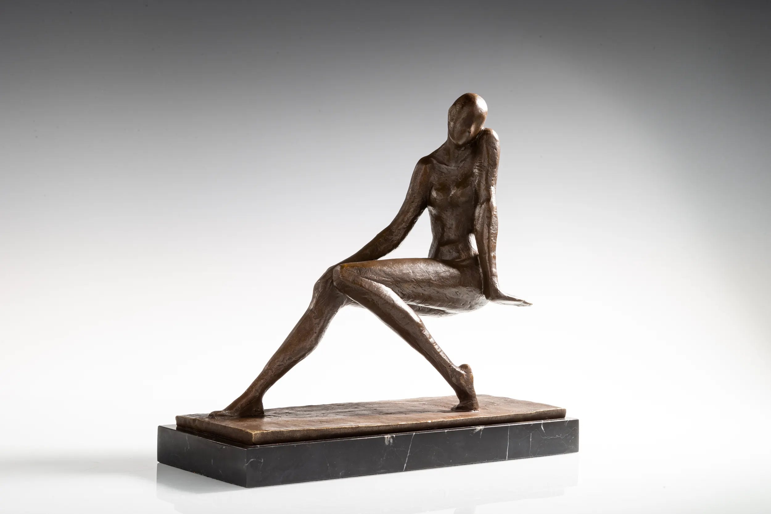 Front view of thoughtful seated woman bronze sculpture with tilted head and textured finish