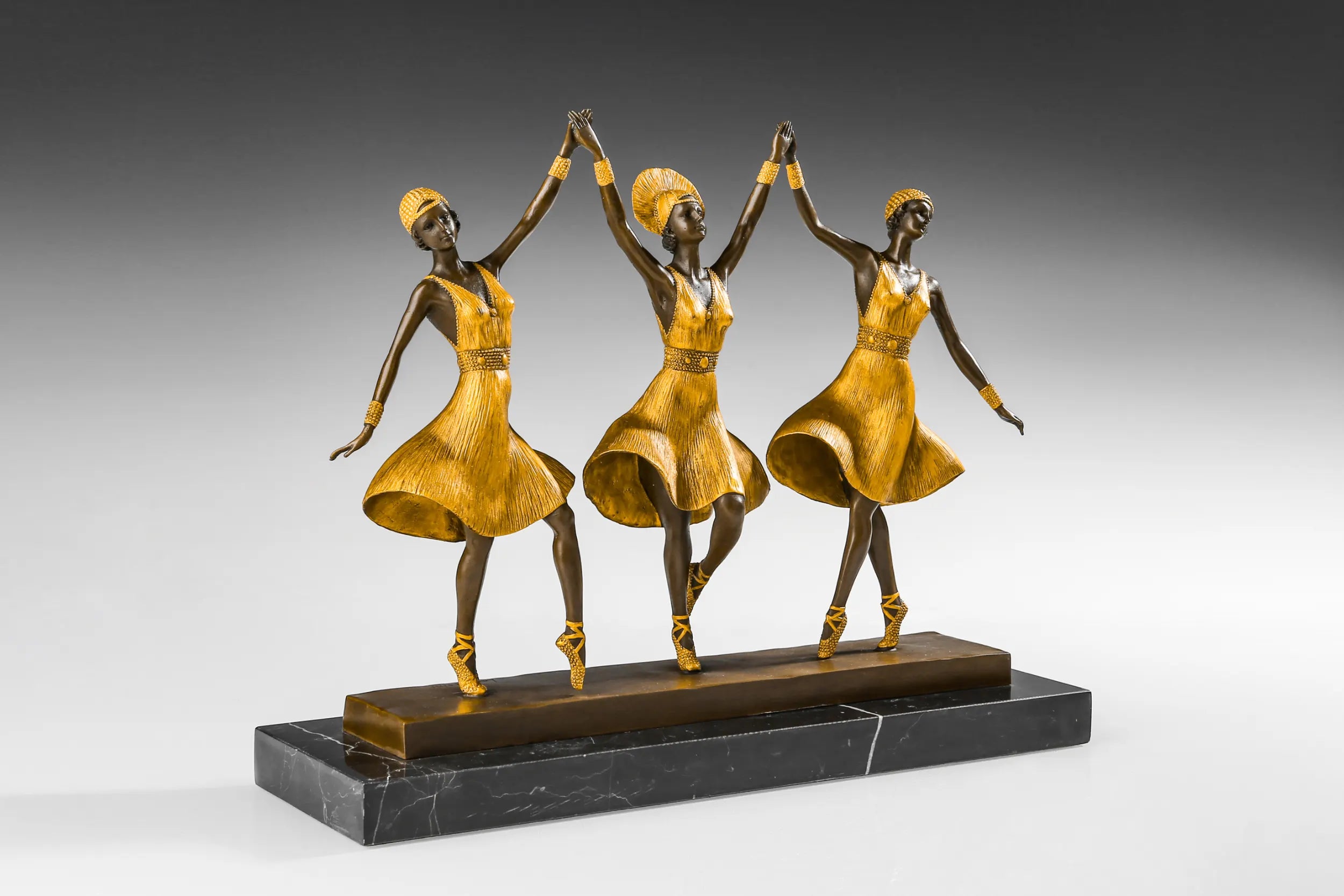 Right side view of three ballet dancers bronze statue with flowing golden skirts