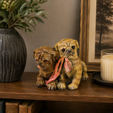 Painted bronze sculpture of two puppies holding a scarf together as cheerful home and shelf decor