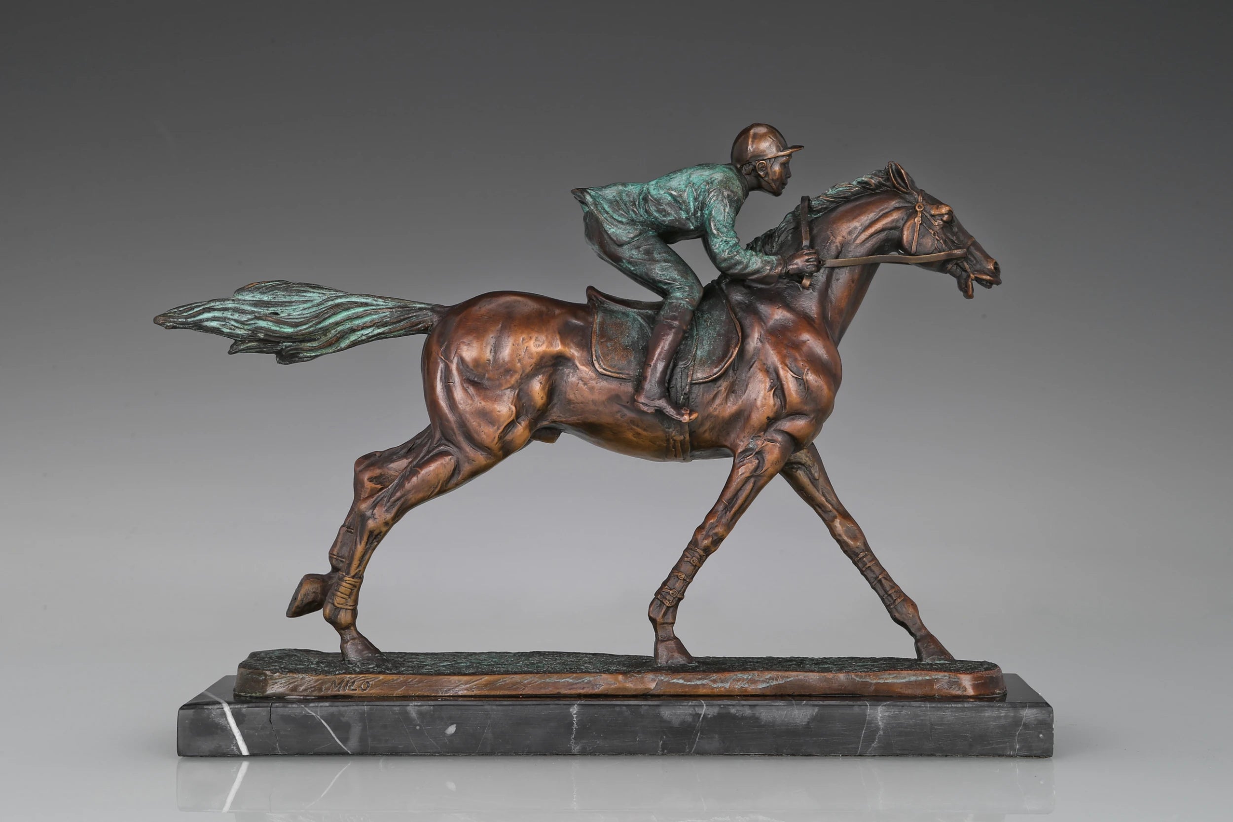 Detail of verdigris green patina on bronze horse racing statue with jockey and saddle accents