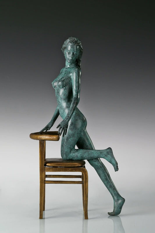 Bronze sculpture of a woman leaning against a golden chair with green patina